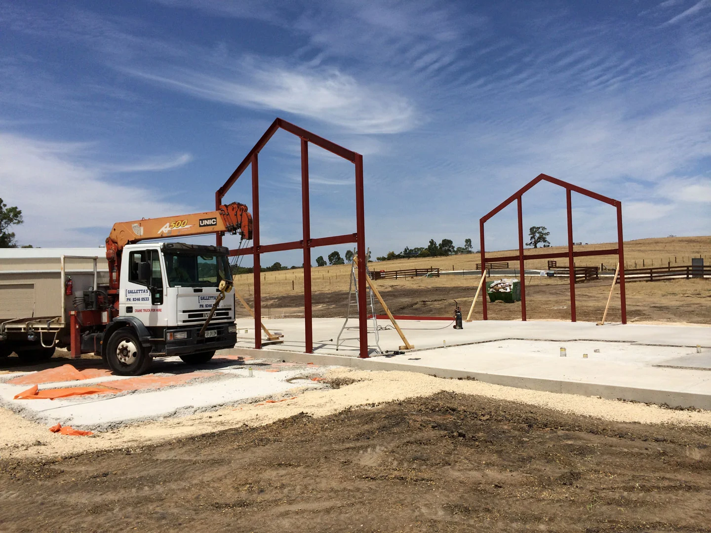 Crane truck delivering a red structural steel frame